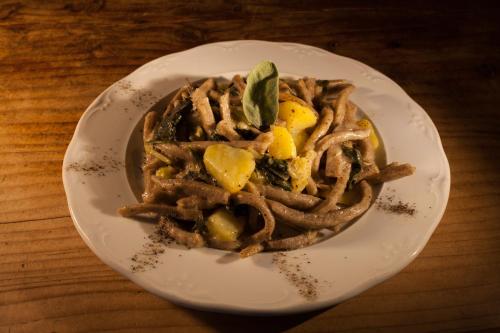 a white plate with a pasta dish on a table at Agriturismo Giacomino in Gera Lario