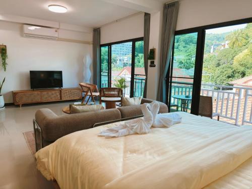 a bedroom with a large bed and a living room at Mr Oh in Phuket Karon in Ka Rorn