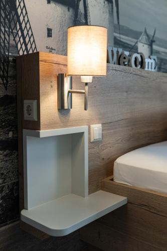 a lamp on a wall next to a bed at Hotel in der Mühle in Werdau