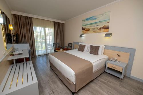 a hotel room with a large bed and a desk at AQI Pegasos World in Side