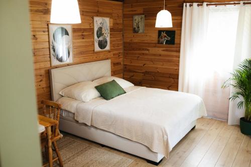 a bedroom with a white bed and wooden walls at Domek U Stefanów - Królowy Most in Królowy Most