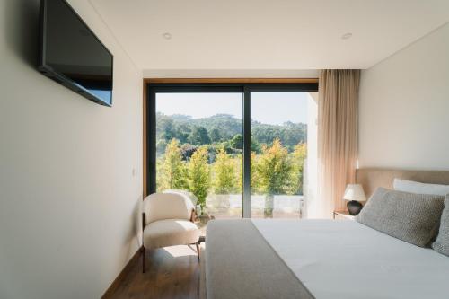 a hotel room with a bed and a large window at Souto Village - Douro Verde - by FERO in Maureles