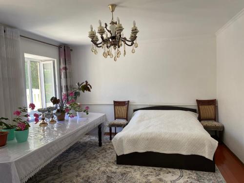 a bedroom with a bed and a table and a chandelier at ASAN ATA Guest House in Toktogul