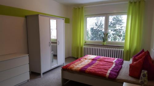 ブルクにあるFeWo an der kleinen Spreeのベッドルーム1室(緑のカーテン、ベッド1台、窓付)