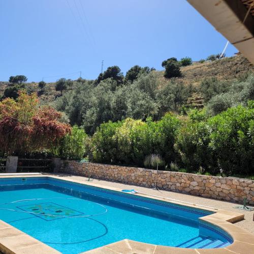 a swimming pool with a hill in the background at Cortijo La Joya in Lanjarón