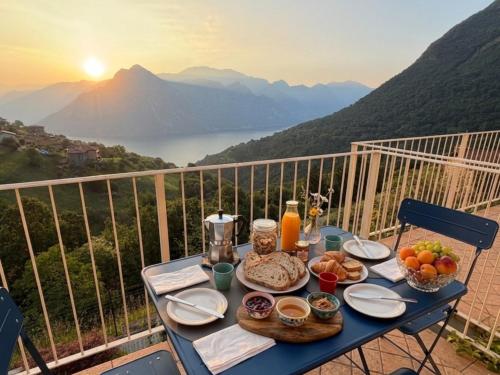 a table with food on top of a balcony with mountains at Lake Iseo View Retreat - Quiet & Nature in Fonteno