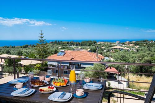 a table with food on a balcony with a view of the ocean at Cataleya - Sea & Sunset View Apartment in Tsoukalades