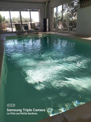 a swimming pool with green water in a building at La Villa Les Petits Gardons in Castillon-du-Gard