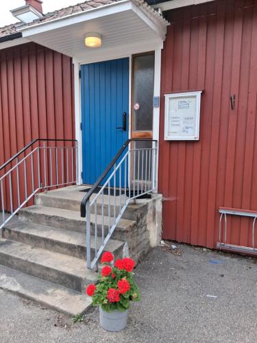a house with a blue door and a plant with red flowers at Vandrarhem Varvet in Ellös