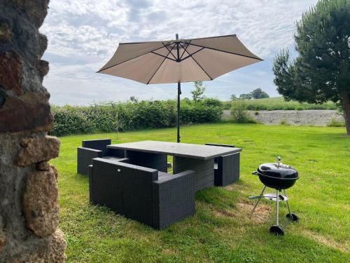 a grill and an umbrella with a grill and a b smoker at gite "La Renaudaie" - piscine in Juvigny-le-Tertre