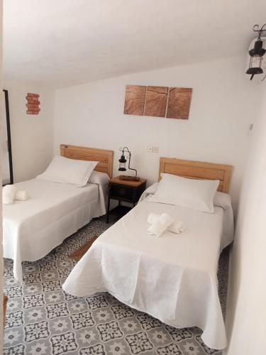 two beds in a room with white walls at Casa de los Abuelos in Cardeña