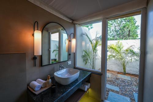 a bathroom with a sink and a large window at Orchard At Sarai - Luxury Tent Villas, Swimming Pool, Large lawns, & Pet friendly in Gurgaon