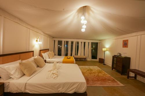 a bedroom with two beds and a large window at Orchard At Sarai - Luxury Tent Villas, Swimming Pool, Large lawns, & Pet friendly in Gurgaon