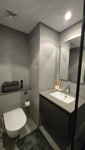 a bathroom with a toilet and a sink and a mirror at Kuro Homes in Sharjah