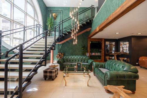 a living room with two green couches and a staircase at Hotel Enziana Wien in Vienna