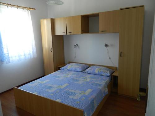 a small bedroom with a bed with a blue comforter at Apartments Skender in Čižići