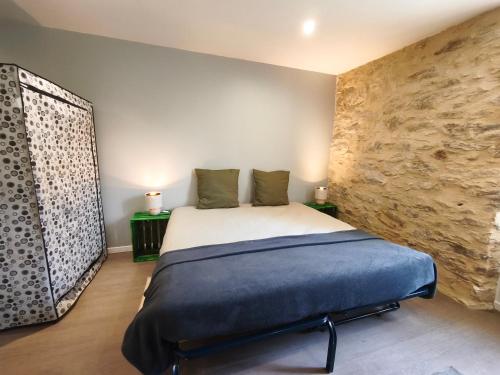 a bedroom with a bed and a stone wall at L'aube de Pierre in Saint-Pons-de-Thomières