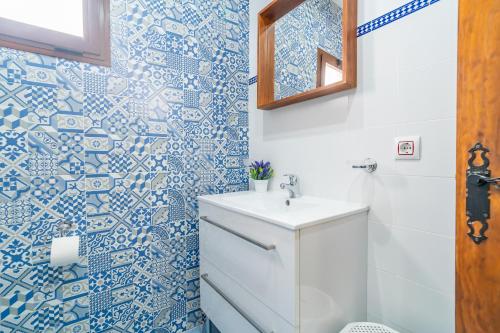 a bathroom with a white sink and blue and white tiles at Casa Rural Casita de la Cantera in La Lantejuela