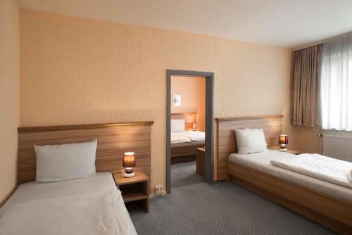 a hotel room with two beds and a mirror at Hotel Weimarer Berg in Apolda
