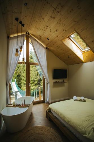a bedroom with a tub and a bed and a window at Lordis Cabin Tihuța in Piatra Fantanele