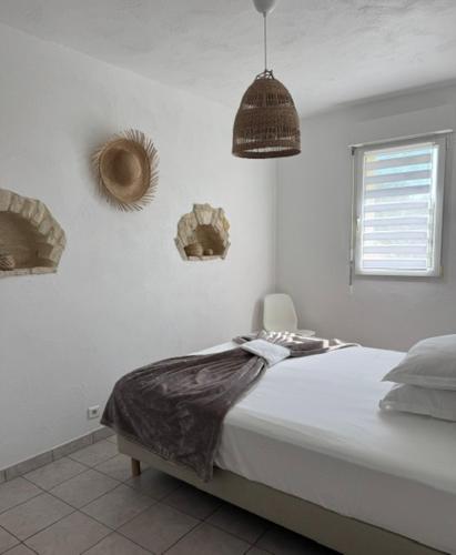 a white bedroom with a bed and a window at L'arbre qui chante in Saint-Étienne-de-Sermantin