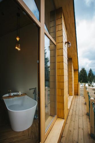 a bathroom with a tub and a glass door at Lordis Cabin Tihuța in Piatra Fantanele