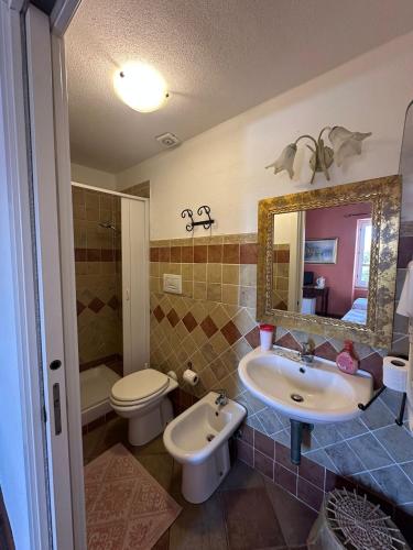 a bathroom with a sink and a toilet and a mirror at Rooms Guest House Il Porto Vecchio in Stintino