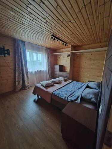 a bedroom with a large bed in a wooden room at Family vacations house in Tīnūži