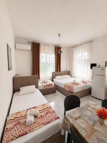 a room with three beds and a table with chairs at Prime rooms in Durrës