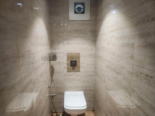 a bathroom with a white toilet and a shower at Hotel Metro Palace L&B in Panvel