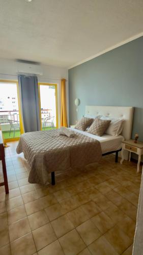 a bedroom with a large bed and a large window at Rocha Paradise Apartment in Portimão