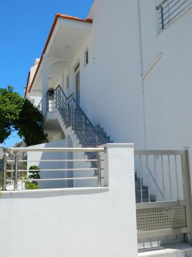 a white building with stairs and a stair railing at Kalithies apartment in Kalithies