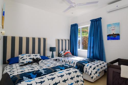 two beds in a bedroom with blue curtains at San Maarten 12 in Sheffield Beach