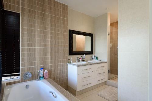 a bathroom with a tub and a sink and a mirror at San Maarten 12 in Sheffield Beach