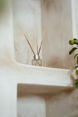 a vase sitting on a white sink with a plant at Agachill Surf House in Tamraght Ouzdar