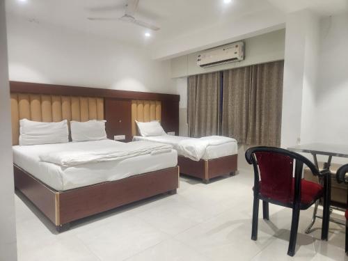 two beds in a room with a table and a chair at Hotel Metro Palace L&B in Panvel