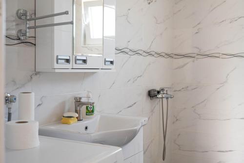 a white bathroom with a sink and a mirror at Apartman Sofija Palić in Palić
