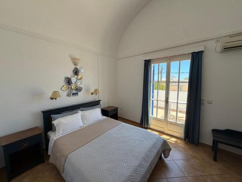 a bedroom with a bed and a large window at Leonidas Apartments in Kamari