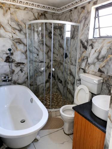 a bathroom with a tub and a toilet and a shower at Springforth Guesthouse in De Grendel