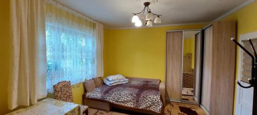 a yellow room with a bed and a window at Вікенд WeekEnd in Kvasy