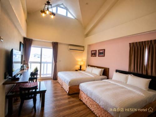 a hotel room with two beds and a desk and a window at He Sen B&B in Kenting