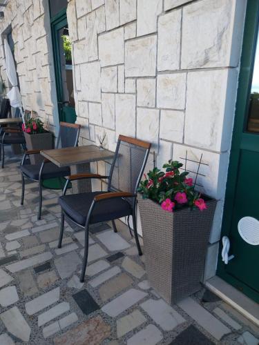 a patio with chairs and a table and flowers at Sobe Kraft 2 in Živogošće