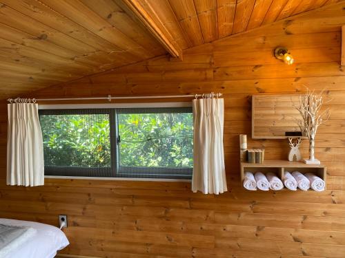 a bedroom with a window in a wooden wall at 서귀포 다붓 in Susal-li