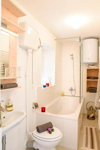 a white bathroom with a toilet and a bath tub at Charming Stone House with Green Courtyard in Stari Grad