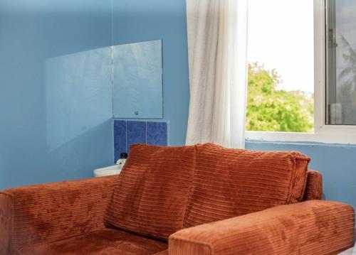 a brown couch in a blue room with a window at Studio in kilifi close to beach and supermarket in Kilifi