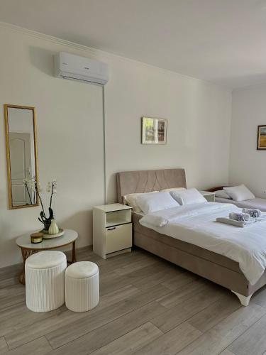 a bedroom with a large bed with two white stools at Camino apartmani in Dračevo