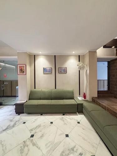 a living room with a green couch in a building at Status Business Hotel - Naveen Market in Kānpur