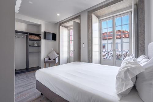 a bedroom with a large white bed and a balcony at Rua Grande Hotel in Viana do Castelo
