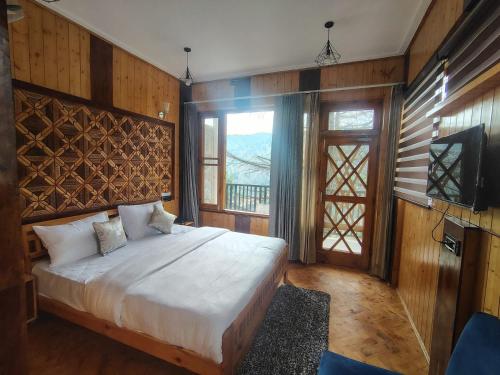 a bedroom with a bed and a television in it at Bhaderwah Resorts Pvt Ltd in Dranga