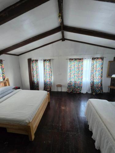 ein Schlafzimmer mit zwei Betten und Fenstern mit Vorhängen in der Unterkunft Pula Re Accomodation in Savusavu